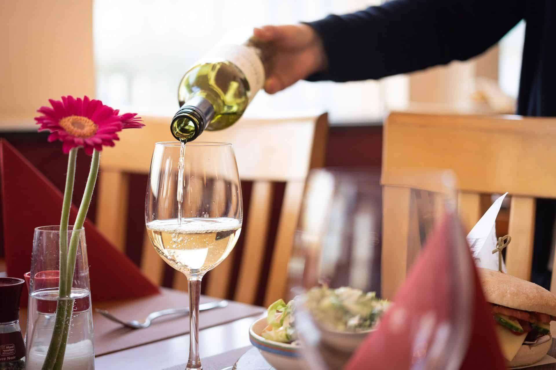 Person-pouring-glass-of-wine-in-restaurant-at-Green-Park-Hotel-Brugge