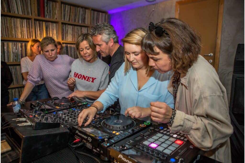Groep mensen aan DJ-tafel met mensen eromheen