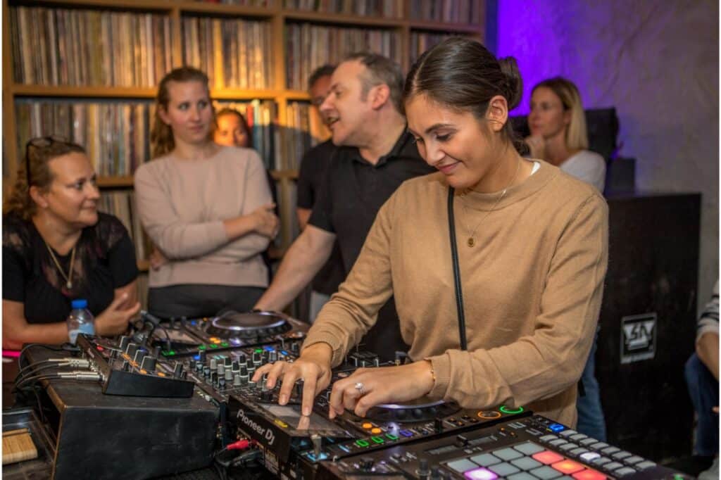 vrouw aan DJ-tafel met mensen eromheen