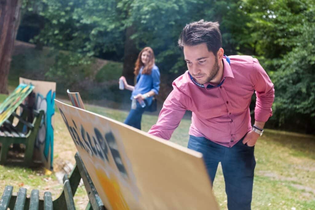 Man spuit graffiti op een bord buiten.
